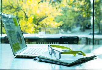 Laptop and glasses on a desk representing organized financial workflows